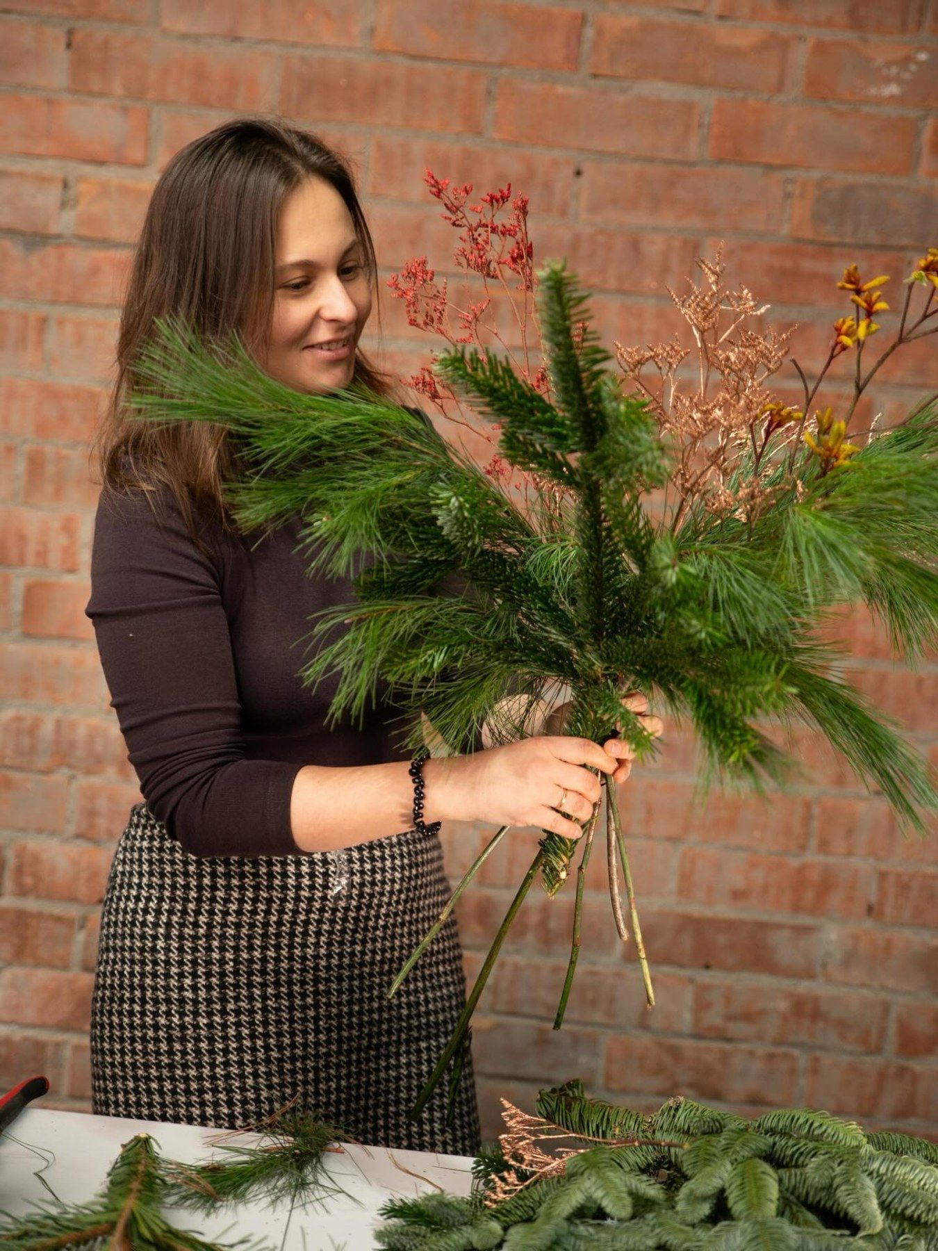 Preparando un ramo de Navidad con ramas de pino en el taller